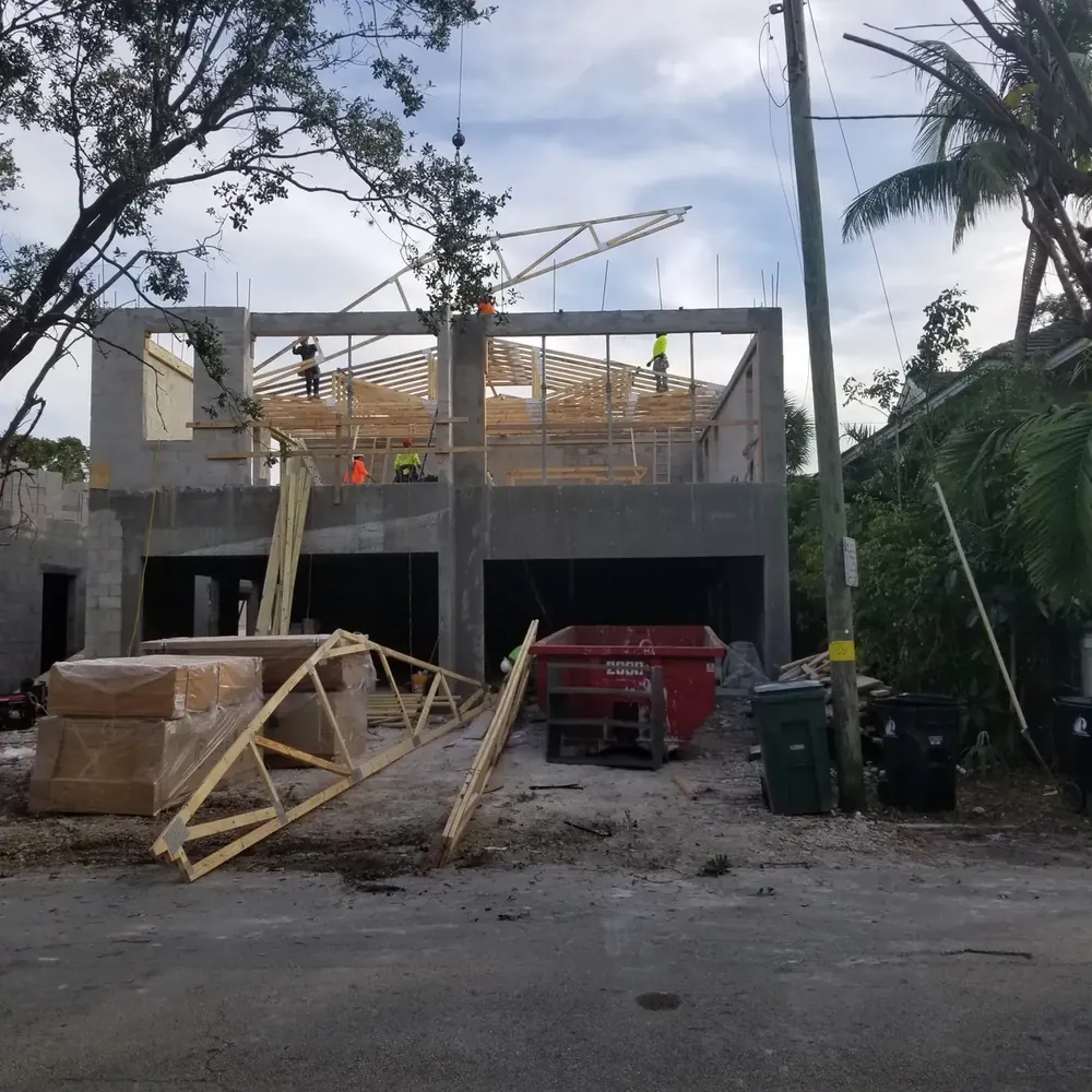 Construction workers framing wooden roof trusses over concrete block walls for a commercial building project in Miami by Booster Construction.