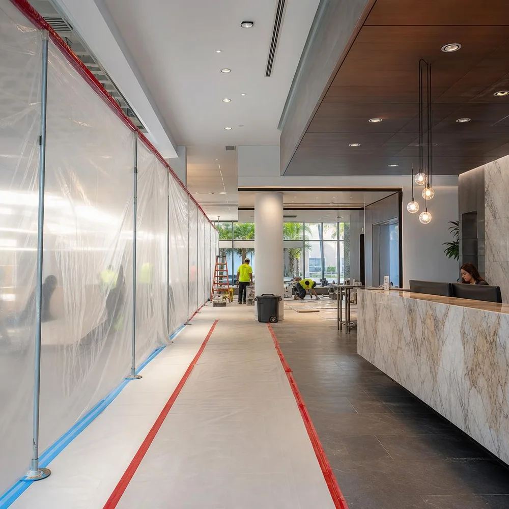 Occupied commercial lobby renovation with a protected pedestrian path, dust-containment partition, and active reception desk