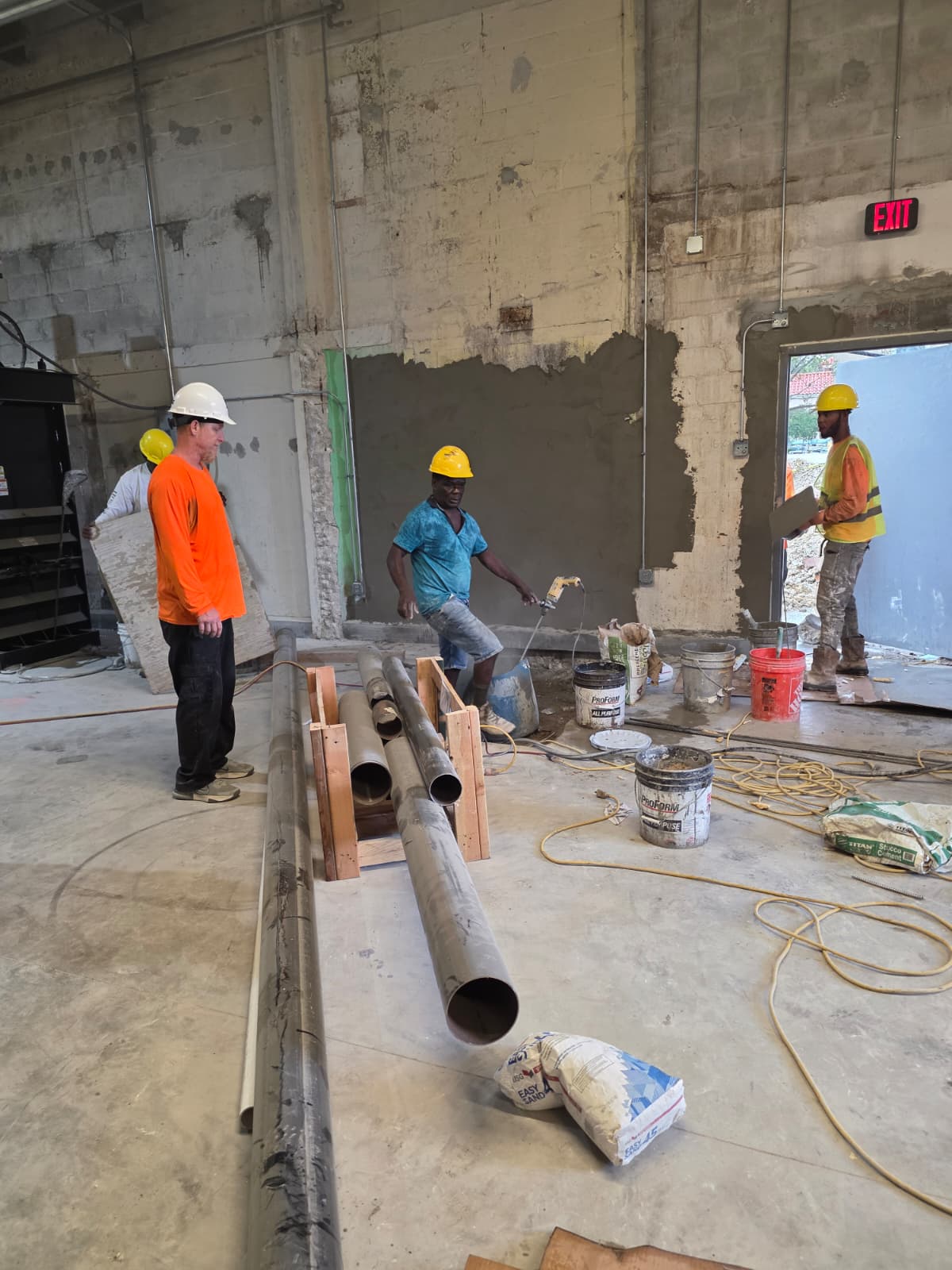 Construction crew in an interior renovation area with exposed masonry, materials, and equipment