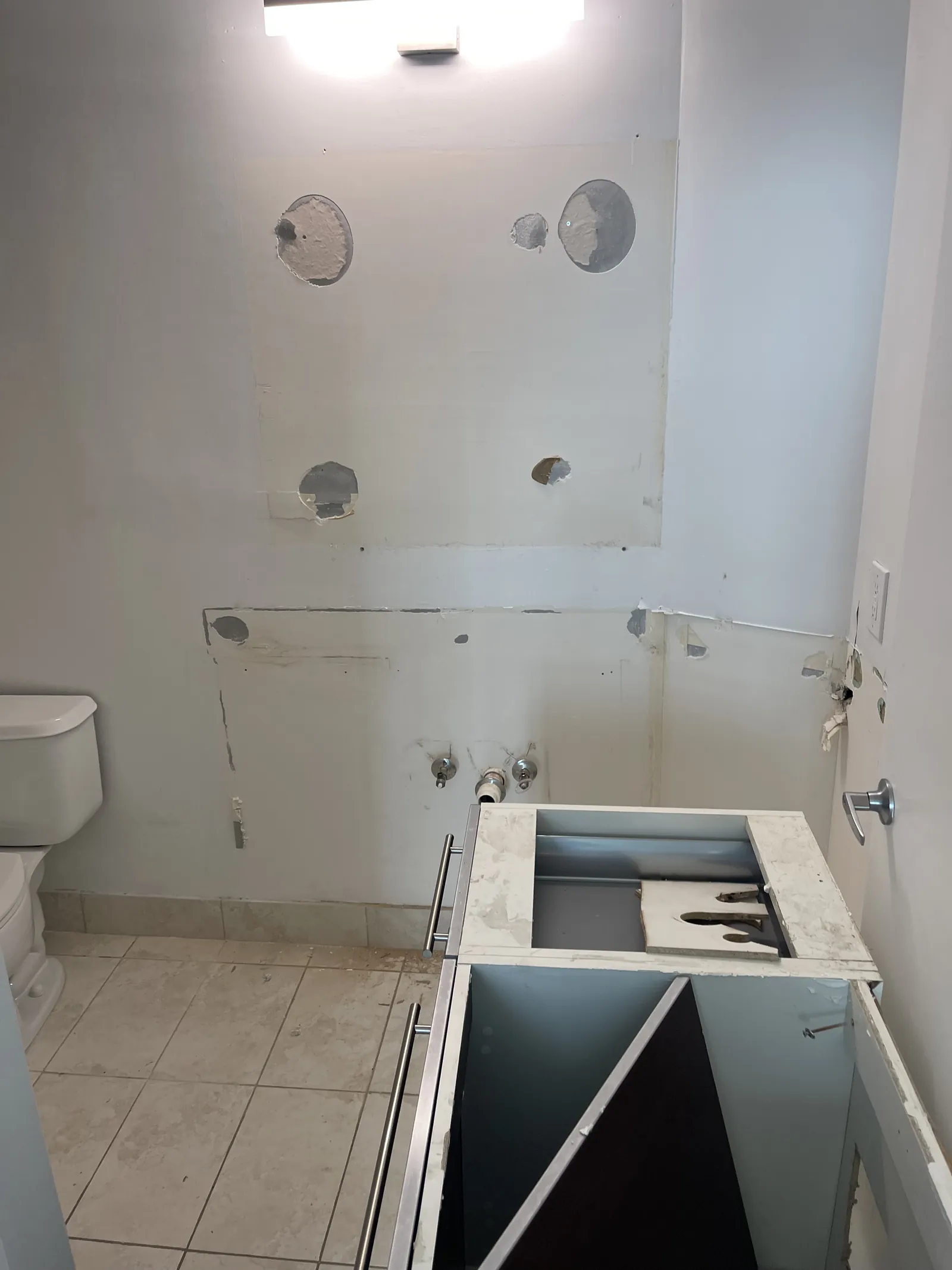 Bathroom renovation with a removed vanity fixture and exposed plumbing connection locations