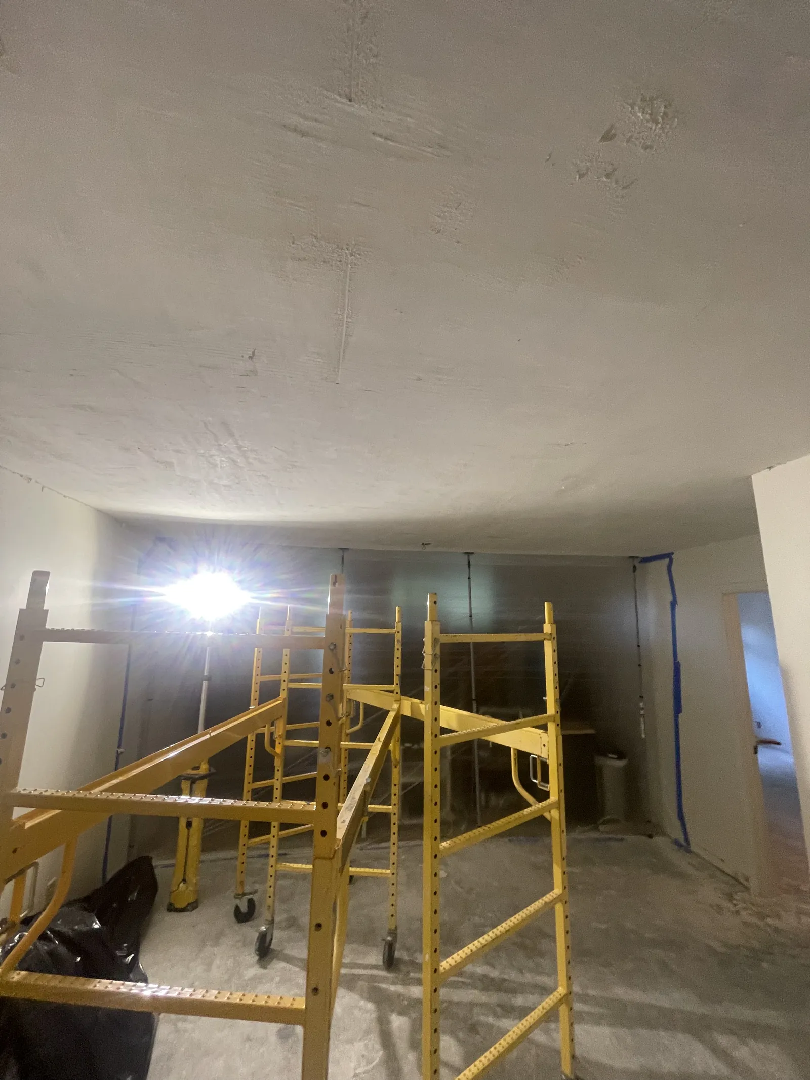 Interior renovation work area with yellow rolling scaffolds, exposed surfaces, and temporary protection