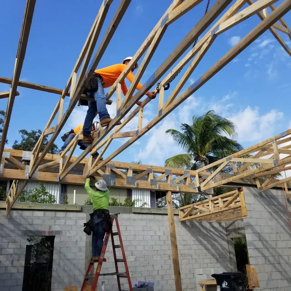 Booster Construction contractors installing wooden roof trusses on a two-story commercial concrete block building in Miami.